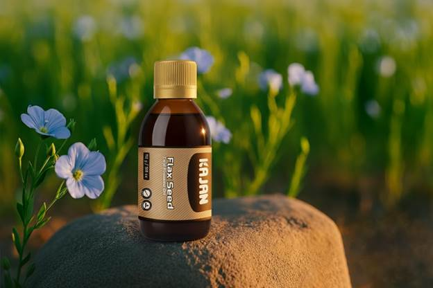 A bottle of Kajan flax seed oil with a beige label and cap sits on a rock. In the background, out-of-focus blue flowers and green foliage create a natural setting.